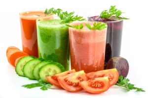 Assorted fresh vegetable smoothies, perfect for health enthusiasts and those practicing intermittent fasting, with corresponding ingredients displayed in front.