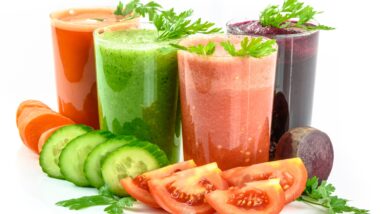 Assorted fresh vegetable smoothies, perfect for health enthusiasts and those practicing intermittent fasting, with corresponding ingredients displayed in front.